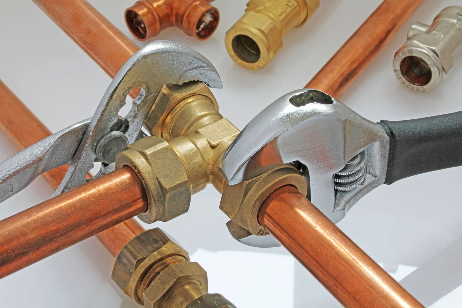two adjustable wrenches tightening up tee-fitting on 15 mm copper pipework with loose pipe in background